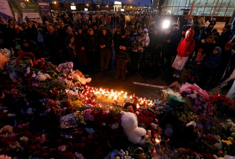 People stand by a memorial to the victims of a shooting attack outside the Crocus City Hall concert venue near Moscow, March 23, 2024. REUTERS