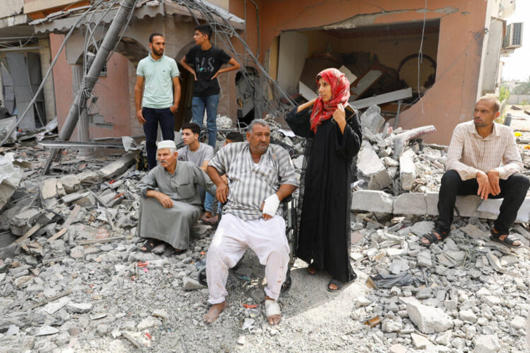 Palestinians watch the civil defense team as they search for victims trapped under the rubble of a house destroyed during Israeli strikes, in Khan Younis, in the southern Gaza Strip, October 8, 2023. REUTERS