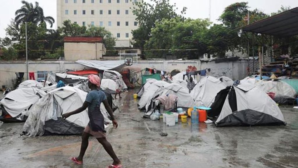 A woman strolls by shelters set up at Gymnasium Vincent, repurposed to accommodate individuals displaced by gang violence, in Port-au-Prince, Haiti.