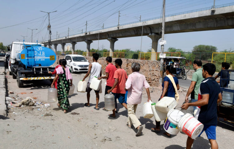 New Delhi, June 16: Residents of Ashok Nagar carrying a filled water container after collecting water from the Delhi Jal Board water supply tanker amid the water crisis in the city, in New Delhi on Sunday.