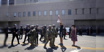 A protester holds a sign up to California National Guard and LAPD outside the federal building to denounce the ICE, U.S. Immigration and Customs Enforcement, operations. (Image- AP)
