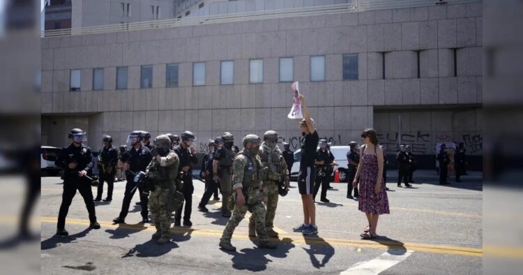 A protester holds a sign up to California National Guard and LAPD outside the federal building to denounce the ICE, U.S. Immigration and Customs Enforcement, operations. (Image- AP)